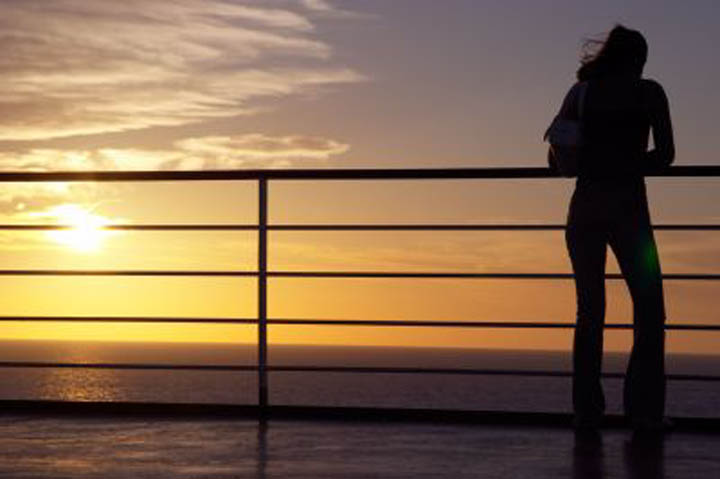 A woman is standing near a railing looking over the water, thinking about letting go of her relationship.