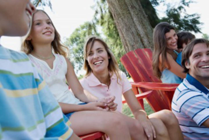 A beautiful woman spends time with her boyfriends family at a picnic when her boyfriend is out with his friends.