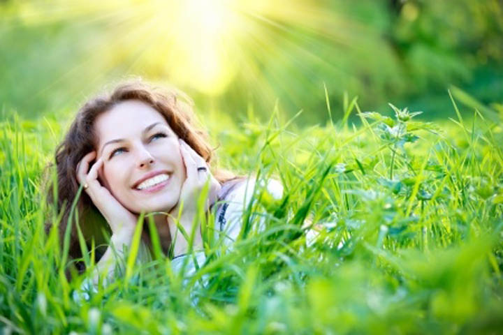 Beautiful, confident woman laying in the grass smiling. 