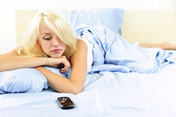 A beautiful woman looks at her phone wondering why he hasn't called.