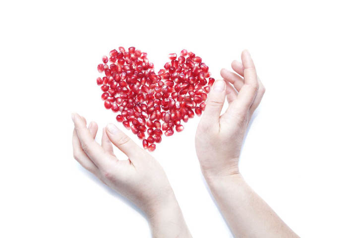 A woman's hands surrounding red seeds in the shape of a heart, representing planting the seeds of love.