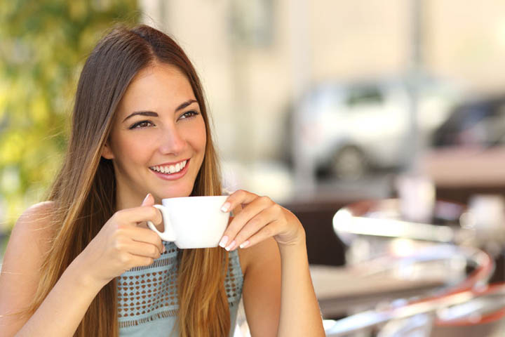 A beautiful woman is on a date, smiling from across the table.