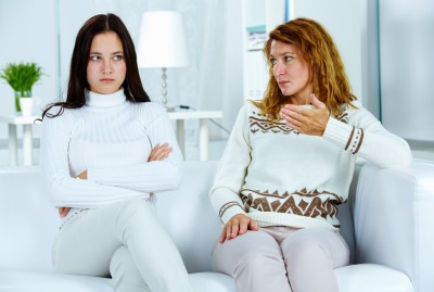 Whether we recognize it or not, your mom has a say in who you become and even who you date. A beautiful mother sitting on the couch with her beautiful but upset daughter.