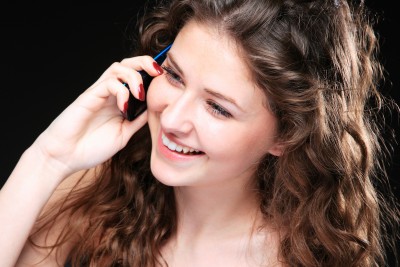 A beautiful brunette woman is smiling and talking on her cell phone trying to keep an open mind