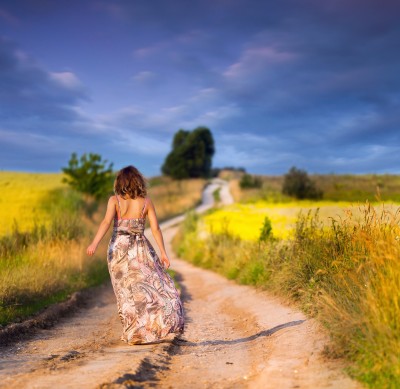 A beautiful woman is walking down a path in a field of yellow flowers, representing her journey towards learning to love herself and finding true love.