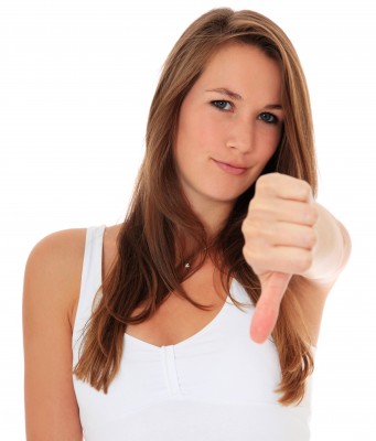 A beautiful woman with long blond hair in a white tank top is pointing her thumb down indicating that she is being picky in her relationships. She is picky because she knows what she wants and deserves.
