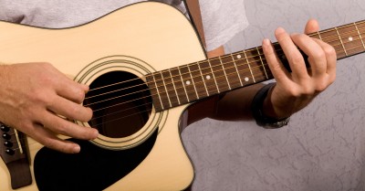 A man plays acoustic guitar while singing about commitment to his girlfriend who wants a commitment.