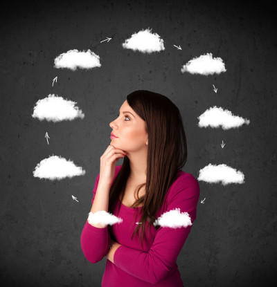 A beautiful woman in a purple shirt against a blackboard with drawn clouds circling around her wonders how her hidden beliefs are ruining her love life. 