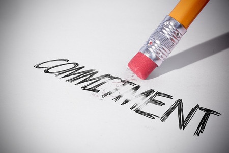 A pencil erasing the word commitment written on white paper, symbolizing a man who suffers from commitment phobia and won't commit or make a commitment and is afraid of a committed relationship.