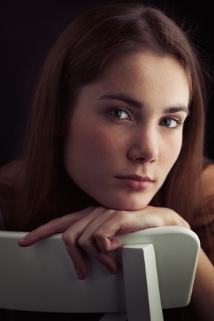 A beautiful woman leans her chin in her arm on a chair, thinking about why she was unable to set boundaries with her previous boyfriend.