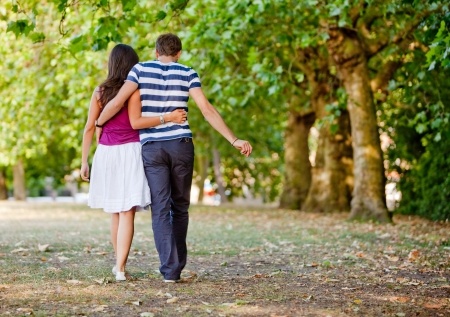 A couple is seen from behind walking arm-in-arm down a wooded path, indicating that she has finally gotten past emotionally unavailable men.