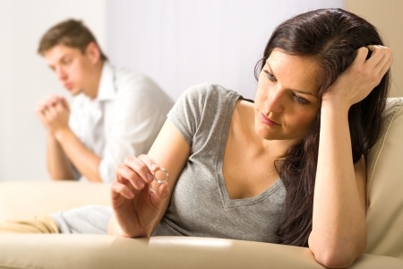 A beautiful woman sits near her emotionally distant boyfriend looking sad as she wonders if she should just move on.