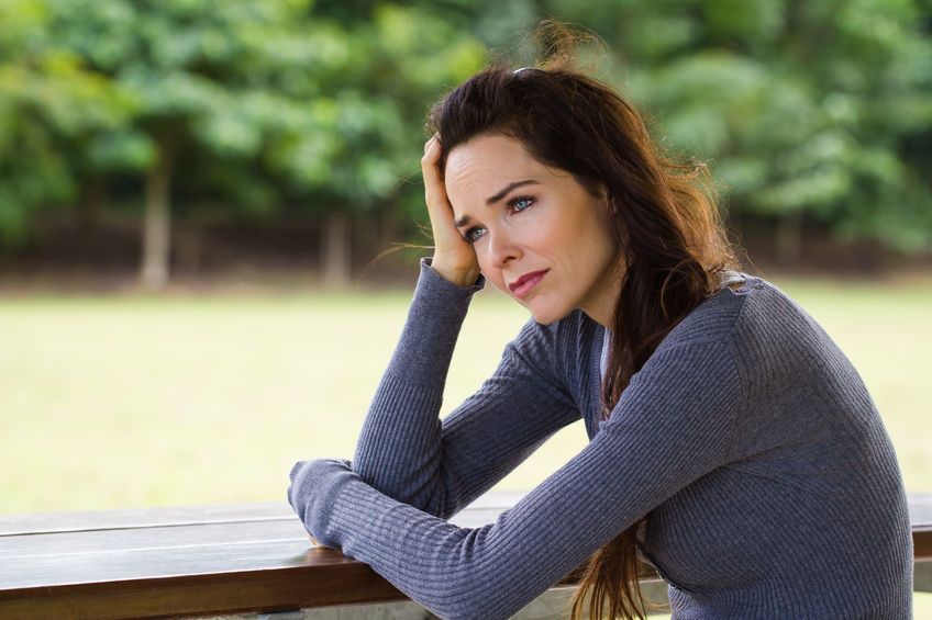 A beautiful woman sits on a deck feeling frustrated at her boyfriend for acting like a man child.