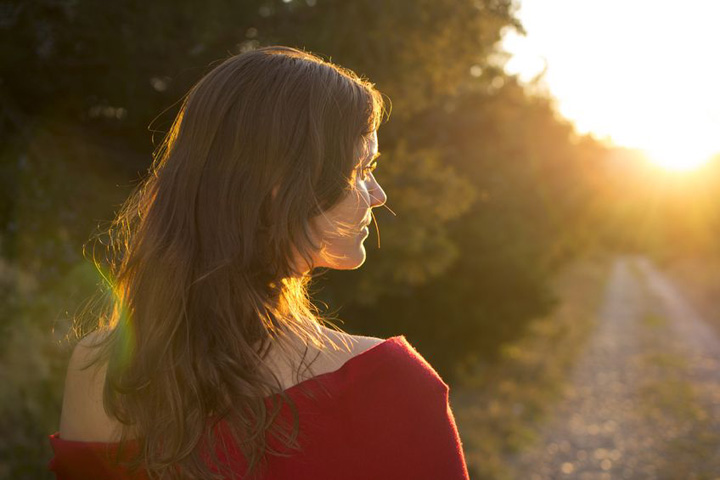 A beautiful woman walks down a path towards the light symbolizing trying to move on from a man who won't commit.