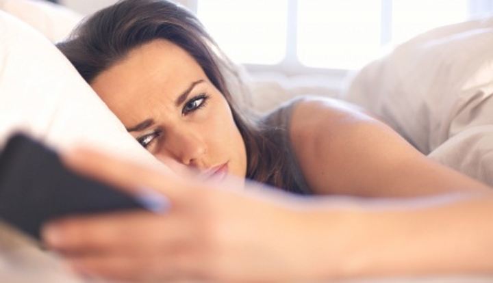 A beautiful woman looks at her phone wondering why her boyfriend suddenly became emotionally unavailable and stopped calling or texting.