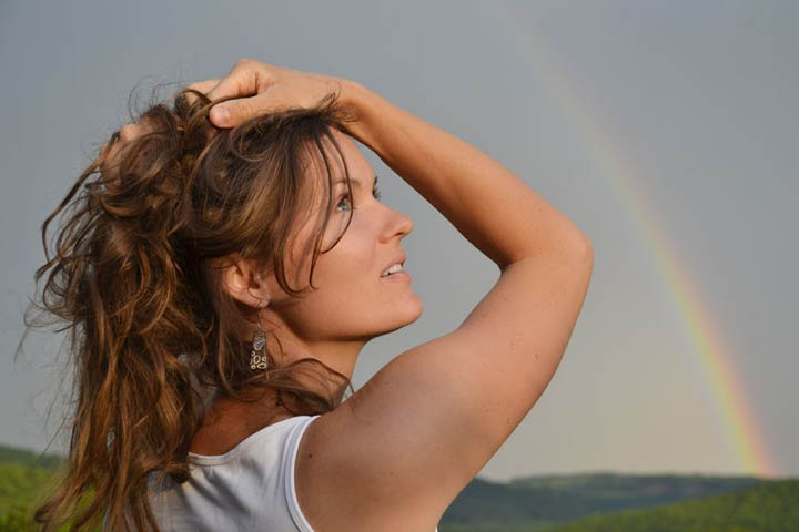 A beautiful woman looks at the sky with a rainbow in the distance symbolizing hope.