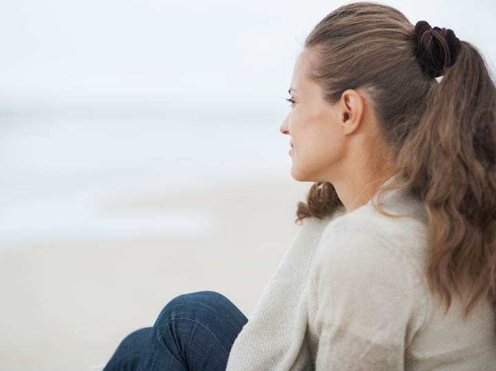 A beautiful woman looks out over the beach, wondering why her boyfriend suddenly disappeared.