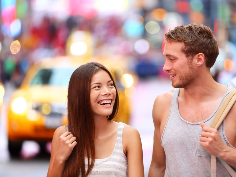 A beautiful woman walks in the city with a guy that is keeping her in the friend zone.