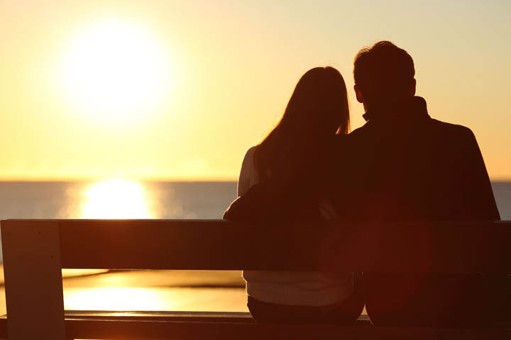 Silhouette of a woman and man watching the sunset over the ocean.