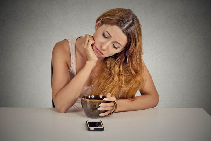 A beautiful, sad woman looks at her phone wondering if he'll ever talk to her again.