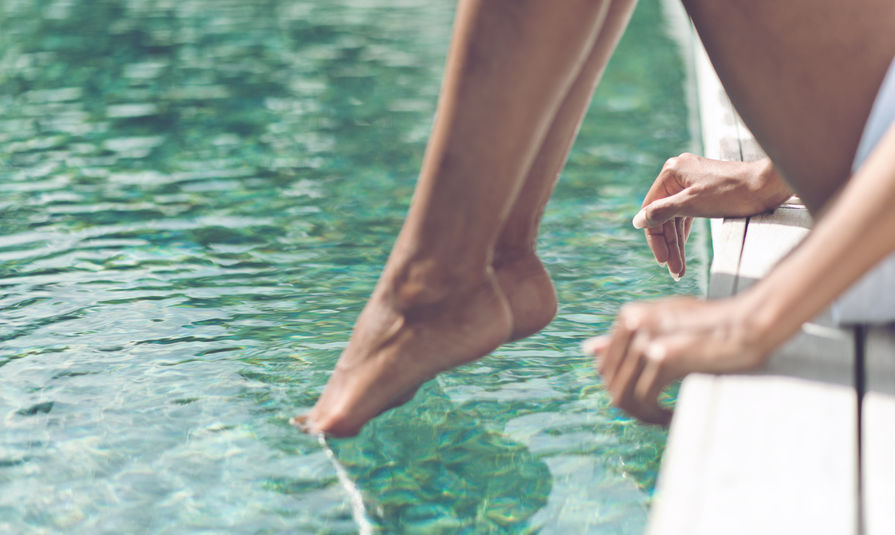 A woman dips her toes in the pool, signifying the half-in-half-out relationship.