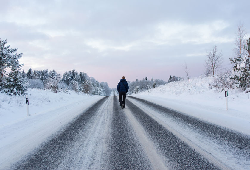 A man walks down a snowy winter road.