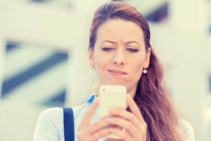 A beautiful woman is confused while reading a text from her boyfriend.