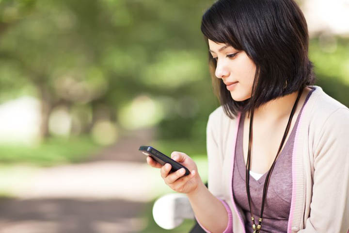 A woman looks at her phone while texting.