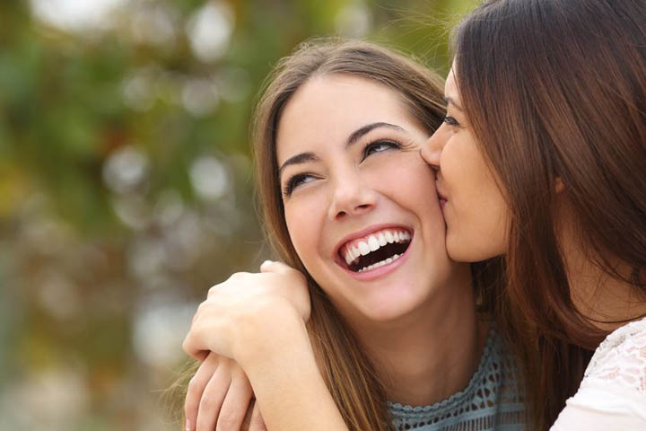 woman laughing while a friend is kissing her representing someone to believe in you.
