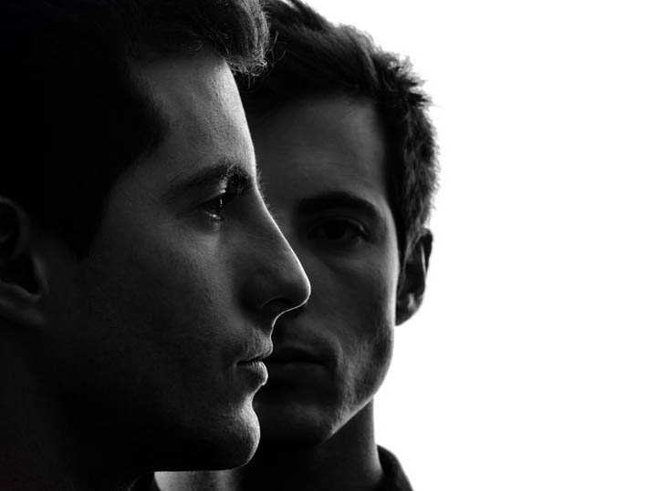 Close up portrait two young men in shadow white background