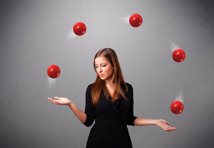 Pretty woman standing and juggling with red balls representing dating multiple men at one time.