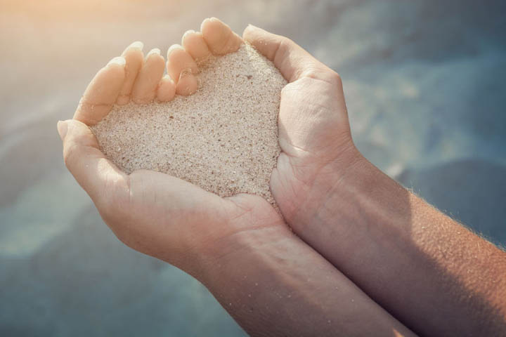 Female hands holding a sand in form of the heart