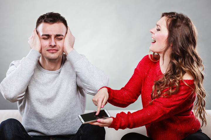 Angry girlfriend shouting at boyfriend showing text messages from other woman on his mobile phone.