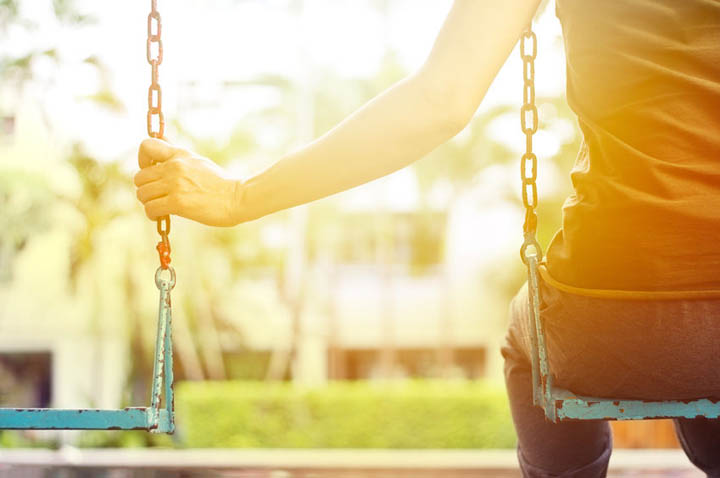 Lonely woman missing her boyfriend while swinging in the park in the morning