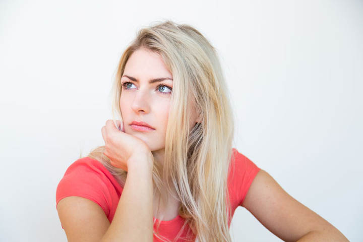 A beautiful woman looks confused and drained with her chin resting on her palm.