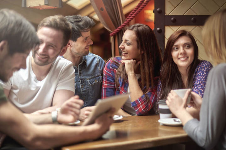 A group of male and female friends are out together socially at a restaurant.