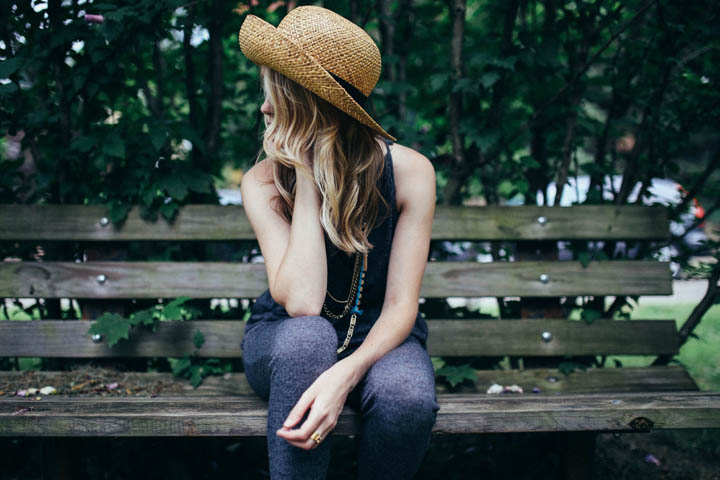 A beautiful woman sits on a park bench wondering why she loves him.