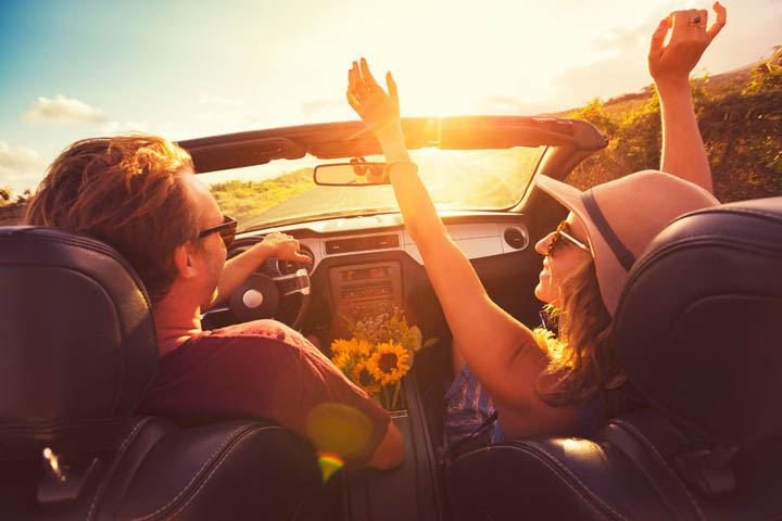 Happy young man and woman driving along country road in convertable at sunset. freedom adevnture roadtrip!