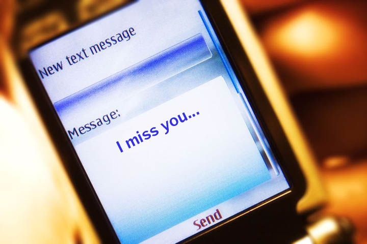 A text message on a mobile phone reads I miss you.