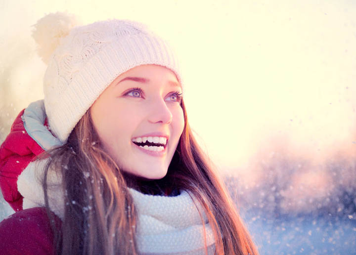 Beautiful woman outdoors in frosty winter park with snowflakes.