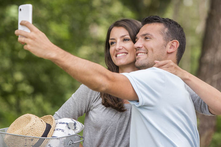 Young couple in love, on bicycles, with man taking a selfie.