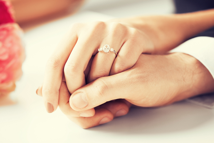 Woman wearing wedding ring holding the hand of her husband celebrating their marriage wedding anniversary