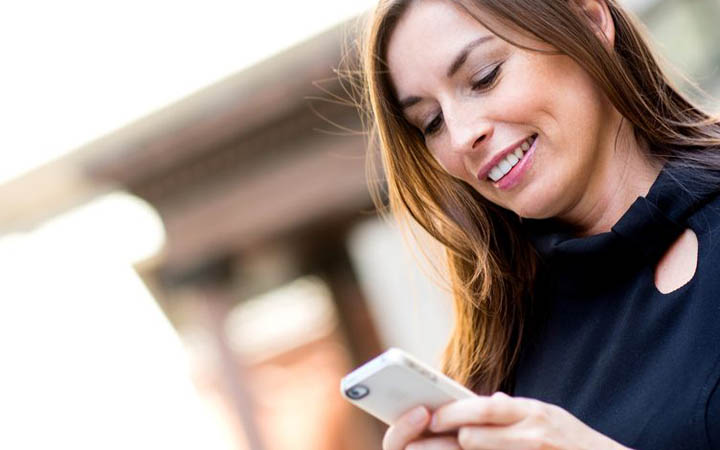 Beautiful woman smiling at text on phone from her new boyfriend.