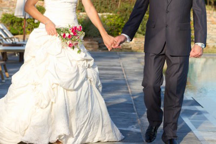 A woman and man are walking holding hands after their wedding.